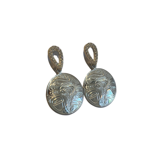 Pair of silver earrings with intricate designs on a light gray background
