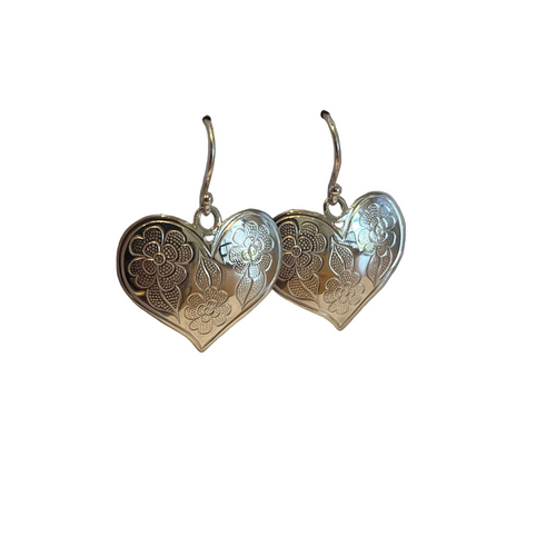 Heart-shaped silver earrings with floral patterns on a light gray background